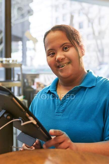 Portrait confiant jeune femme avec trisomie 21 travaillant dans un café — Photo de stock