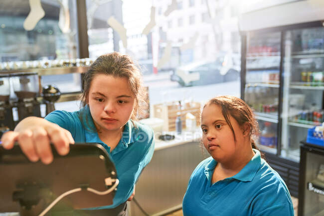 Young women with Down Syndrome working in cafe — Stock Photo