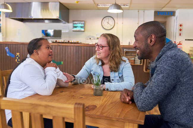 Родители и дочь с синдромом Дауна разговаривают в кафе — стоковое фото