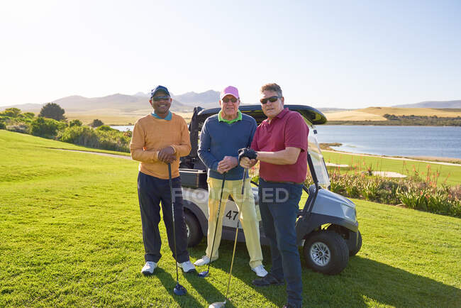 Ritratto fiducioso maturo amici maschi che giocano a golf sul campo da golf soleggiato — Foto stock