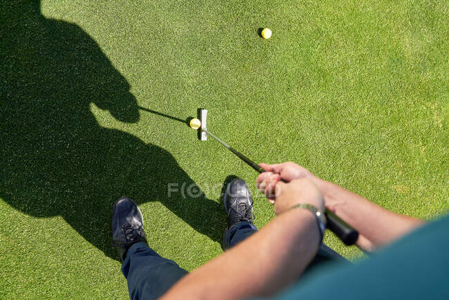 Ponto de vista homem colocando bola de golfe em verdes ensolarados — Fotografia de Stock