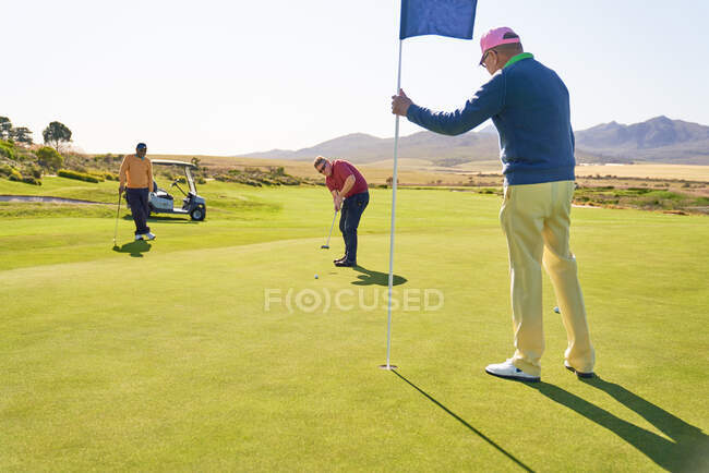 Чоловіки на сонячному гольфі ставлять зелений — стокове фото