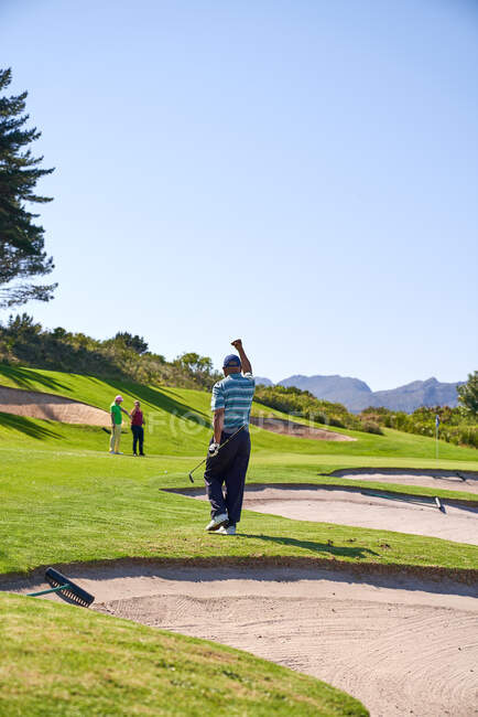 Happy man golfing cheering on sunny golf course — Stock Photo
