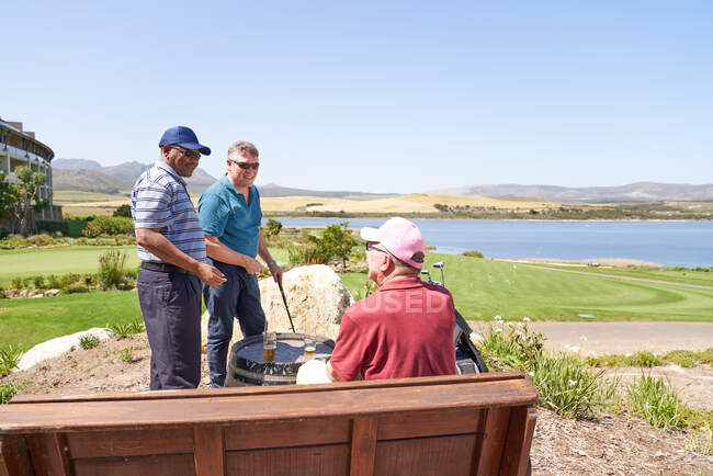 Gli amici golfisti parlano bevendo birra sul patio soleggiato del campo da golf — Foto stock