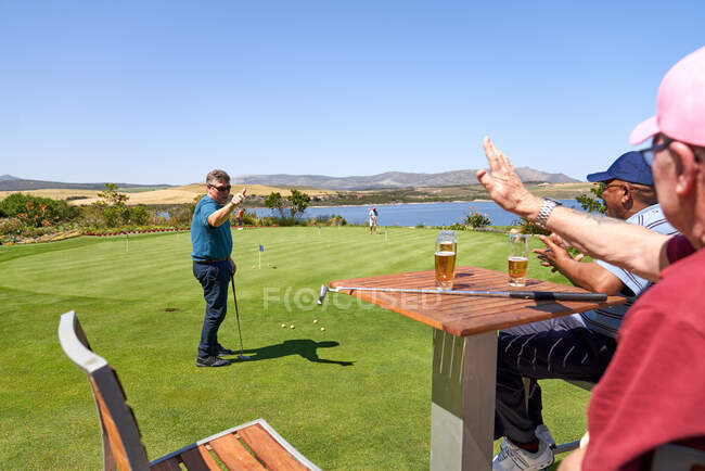 Hombres amigos golfistas beber cerveza y practicar poner - foto de stock