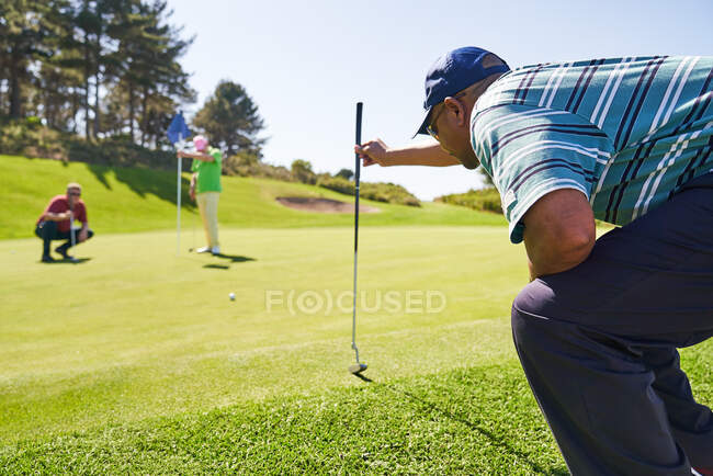 Männlicher Golfer bereitet sich auf Putt auf sonnigem Golfplatz vor — Stockfoto