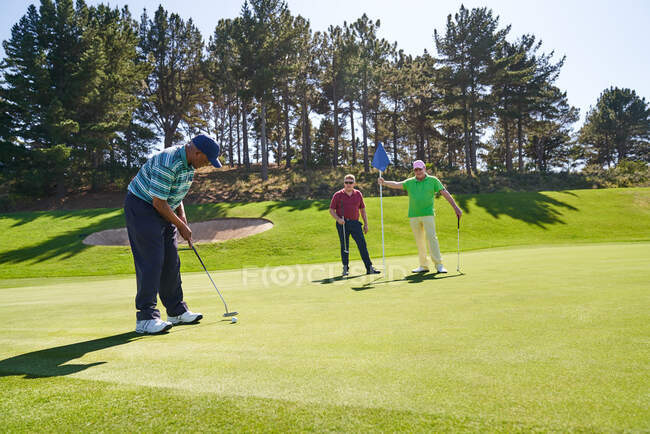 Golfer putting on sunny golf course — Stock Photo