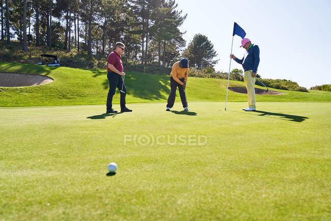 Hombres amigos golfistas poner en casa en el campo de golf soleado - foto de stock