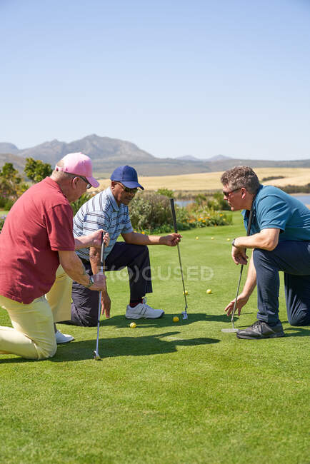 Los golfistas masculinos de rodillas en poner la práctica verde - foto de stock