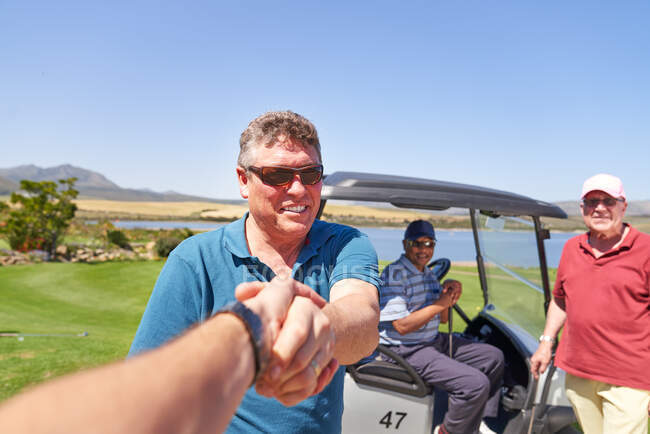 Персональна перспектива чоловічих гольфістів рукостискання на сонячному полі для гольфу — стокове фото