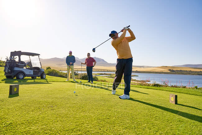 Male golfer teeing off at sunny golf tee box — Stock Photo
