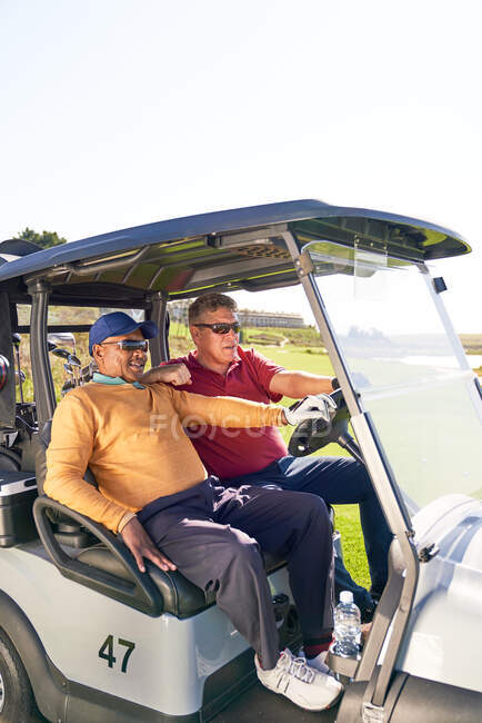 Mature male golfers riding in golf cart — Stock Photo