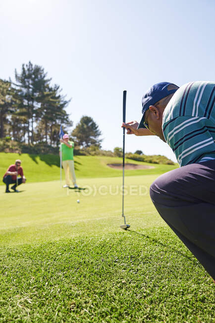 Uomo golfista che si prepara a prendere colpo su sole mettendo verde — Foto stock
