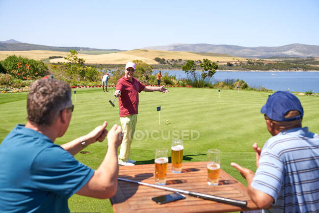 Счастливые гольфисты мужчины пьют пиво и практикуются в игре в гольф — стоковое фото