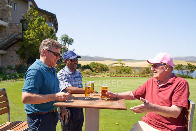 Feliz maduro masculino golfistas beber cerveja no ensolarado golfe campo clubhouse — Fotografia de Stock