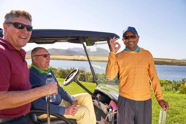 Ritratto felice fiducioso giocatore di golf maschile gesticolando al campo da golf soleggiato — Foto stock