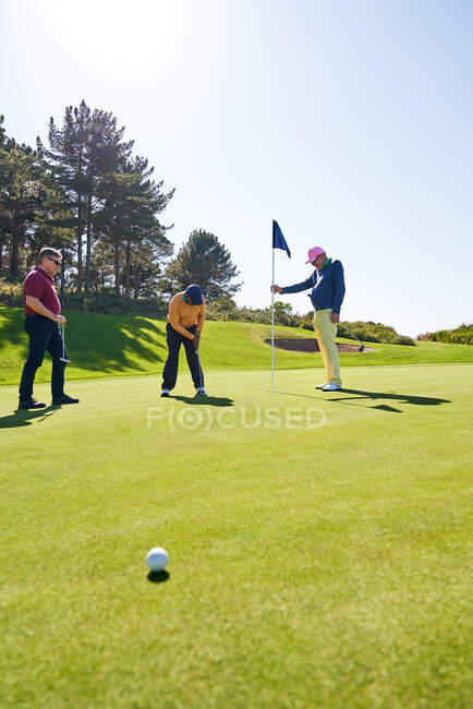 Golfista masculino colocando no buraco no campo de golfe ensolarado colocando verde — Fotografia de Stock