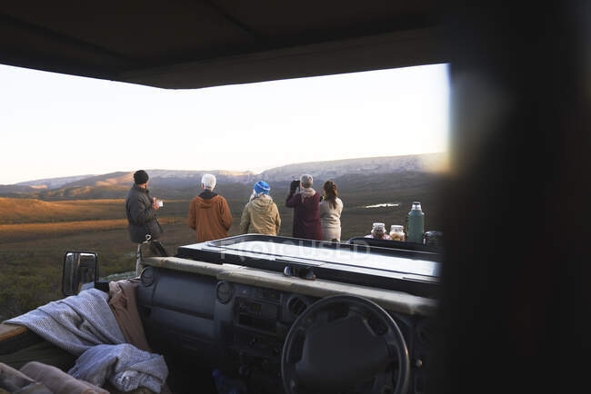 Grupo de safari mirando al paisaje fuera del vehículo todoterreno - foto de stock