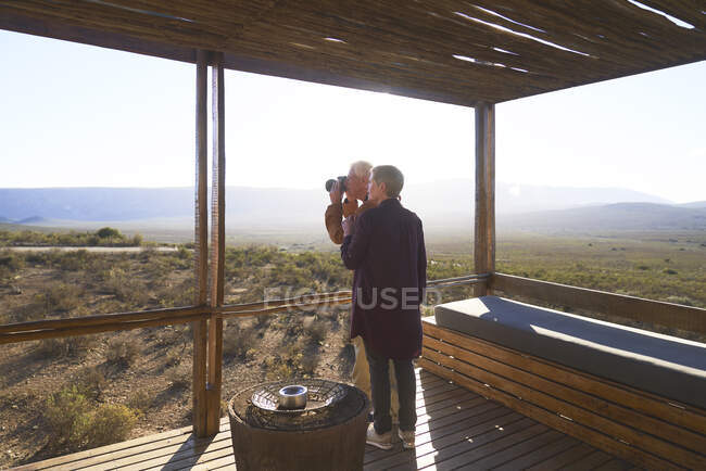 Casal sênior com câmera na varanda ensolarada cabine safari — Fotografia de Stock