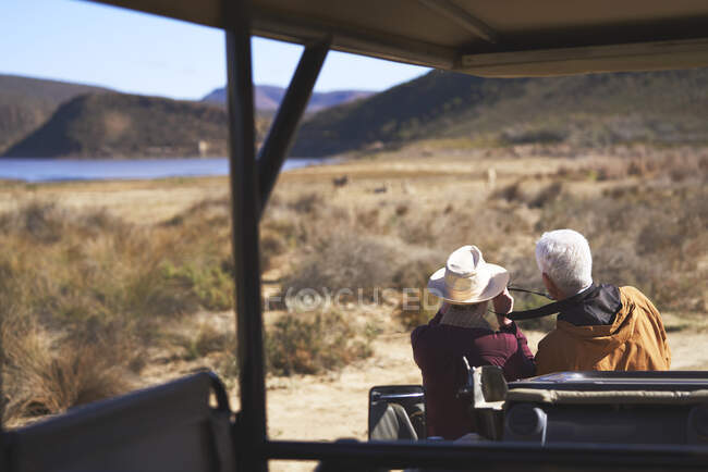 Casal sênior no safari olhando para a vista do lado de fora do veículo off-road — Fotografia de Stock
