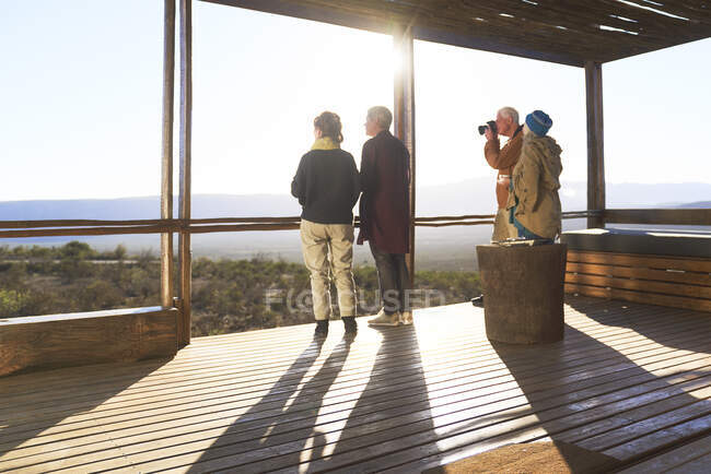 Amigos mirando la vista desde el soleado balcón del albergue safari - foto de stock