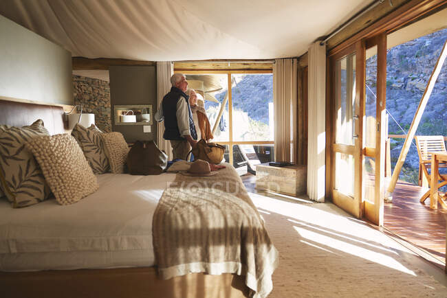 Feliz casal sênior chegando em ensolarado safari alojamento quarto de hotel — Fotografia de Stock