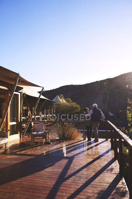 Liebevolles Senioren-Paar umarmt sich auf sonnigem Safari-Lodge-Balkon — Stockfoto