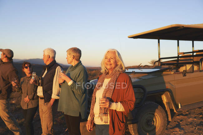 Femme âgée insouciante sur safari boire du champagne au coucher du soleil — Photo de stock