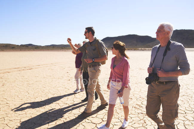 Safari tour guide leading group sunny arid landscape South Africa — Stock Photo