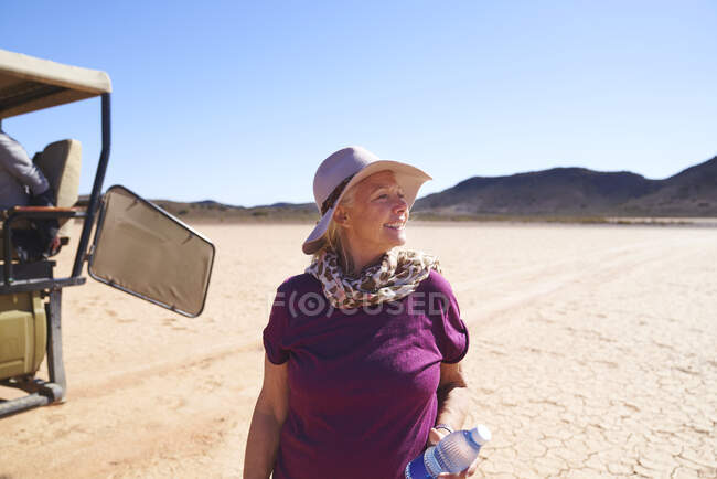 Happy senior woman on safari in sunny arid desert South Africa — Stock Photo