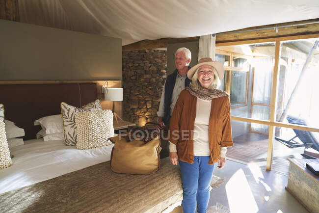 Ritratto felice coppia anziana che arriva in camera d'albergo safari lodge — Foto stock