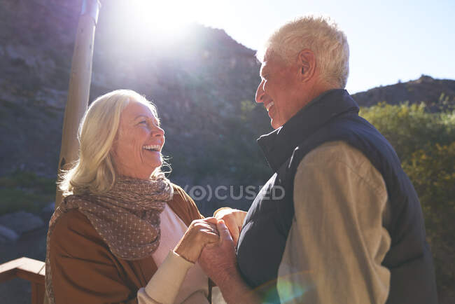 Feliz pareja de ancianos tomados de la mano en el balcón soleado - foto de stock