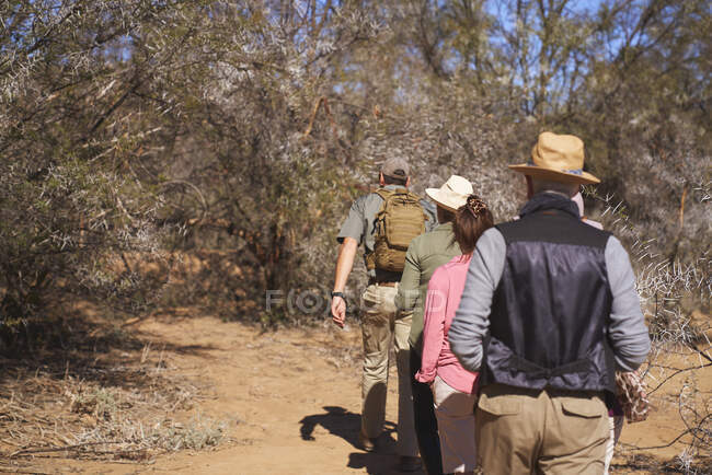 Safari tour guide leading group in sunny grassland South Africa — Stock Photo