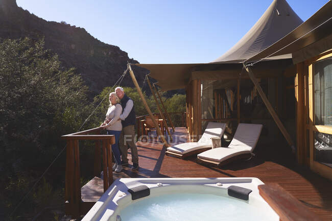 Affectueux couple de personnes âgées sur le balcon du chalet safari de luxe ensoleillé — Photo de stock