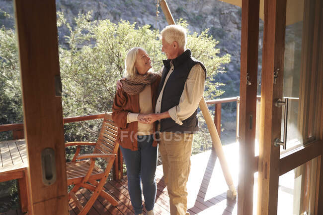 Happy affectionate senior couple on sunny safari lodge balcony — Stock Photo