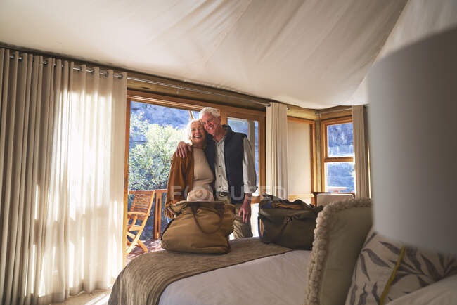 Retrato feliz pareja de ancianos abrazándose en el dormitorio del hotel - foto de stock