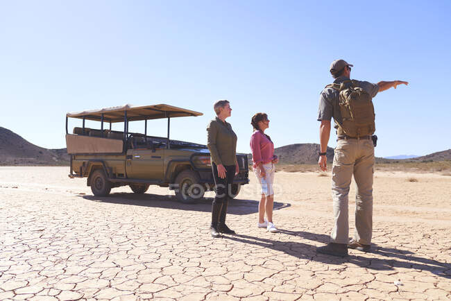 Safari guida turistica parlando turisti nel soleggiato deserto arido Sud Africa — Foto stock