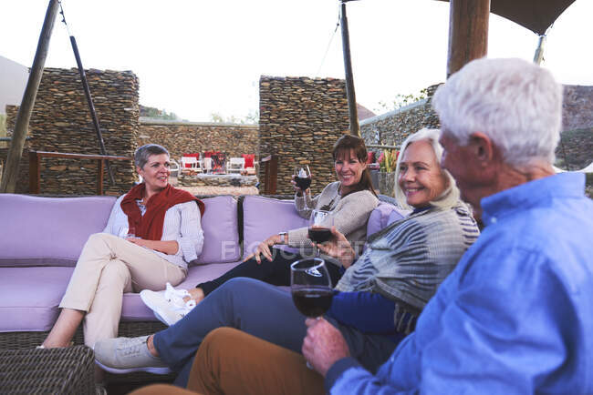 Senior friends drinking wine on hotel patio — Stock Photo