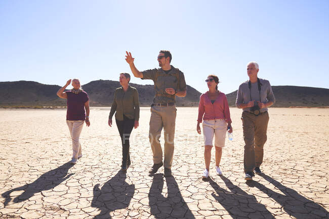 Safari tour guide leading group in sunny arid desert South Africa — Stock Photo
