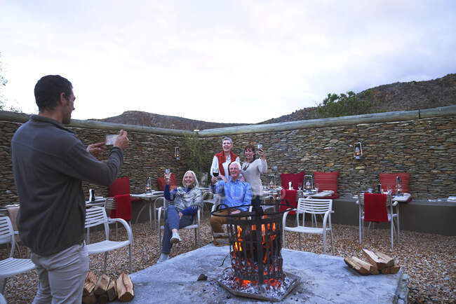 Старші друзі з вином позують для фотографії у вогняній ямі патіо — стокове фото