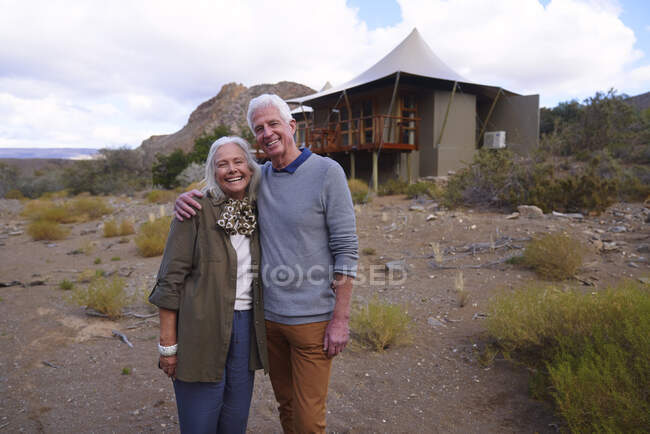 Portrait happy senior couple outside safari cabin — Stock Photo