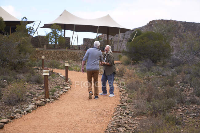 Счастливая пожилая пара, идущая по тропинке возле сафари домика — стоковое фото