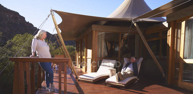Carefree senior couple relaxing on sunny luxury safari lodge balcony — Stock Photo