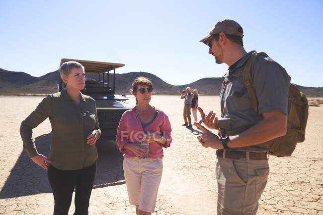 Safari tour guide talking with women in sunny desert South Africa — Stock Photo