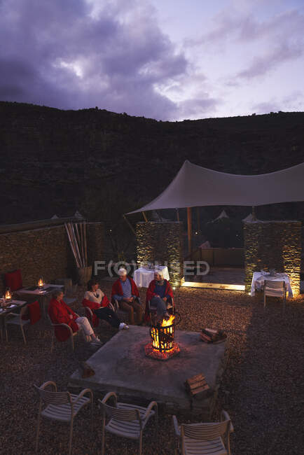 Seniorenfreunde entspannen sich an Feuerstelle auf Hotelterrasse — Stockfoto