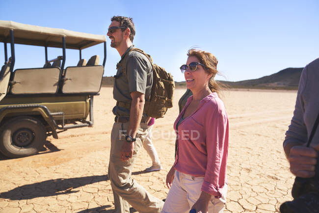 Safari grupo de turistas caminando en el soleado desierto árido de Sudáfrica - foto de stock