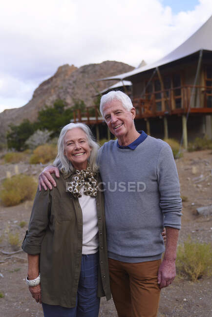 Retrato feliz pareja de ancianos fuera cabaña safari lodge - foto de stock