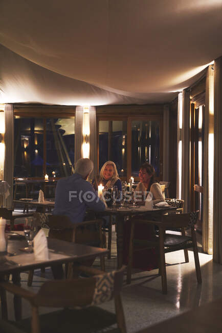 Senior friends dining at candlelight restaurant table — Stock Photo