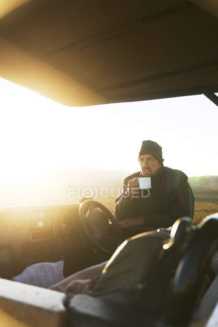 Safari-Reiseleiter trinkt bei Sonnenaufgang Tee im Geländewagen — Stockfoto