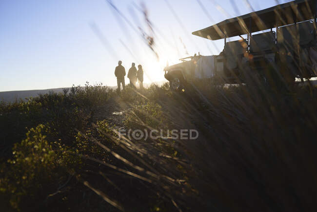 Silhouette safari tour group and off-road vehicle on hill at sunrise — Stock Photo